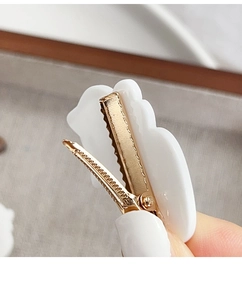 Close-up of white cloud-shaped hair clip with durable golden metal duckbill clip back