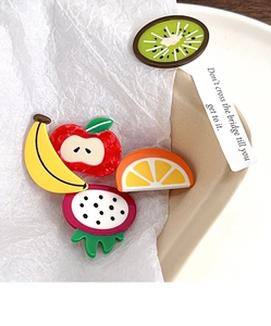 Close-up of cute acetate fruit hair clips in apple, orange, and kiwi shapes on a tray