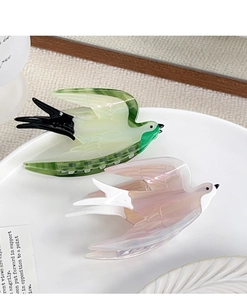 Detailed macro view of acetate swallow hair claws in mint green and gradient pink purple