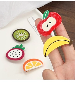 Detailed close-up of colorful acetate fruit hair clips in hand showing size and glossy finish
