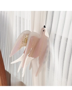 Close-up of bird-shaped claw clip in gradient pearlescent pink and creamy white tones