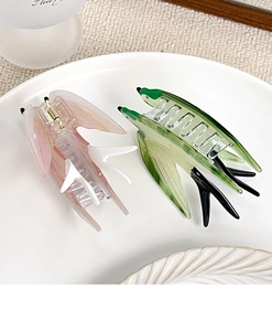 Macro detail of bird-shaped hair claws in marble acetate with strong gold metal springs