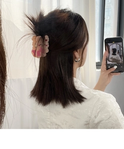 Détail de la pince à cheveux à nœud rose en acétate sur une coiffure demi-haute