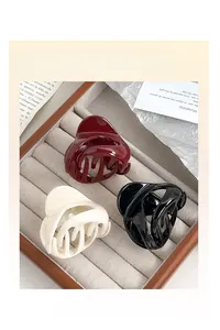 Hair claw clips in burgundy, cream, and black displayed in a wooden jewelry box