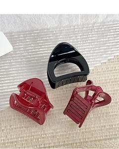 Trois pinces à cheveux triangulaires brillantes noires et bordeaux sur fond texturé