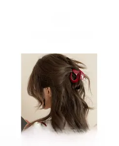 Deep red resin hair claw clip with irregular hollow twist design shown on brown hair