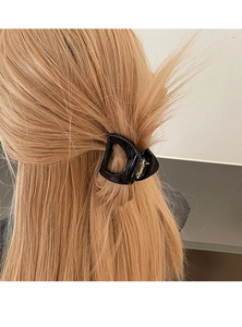 Détail d'une élégante pince à cheveux noire en forme de D pour une demi-queue sur cheveux clairs