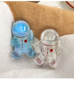 Detail of cute astronaut hair claws in blue and white marble acetate finish