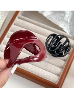Detail of glossy pumpkin-shaped hair claw clips in burgundy and black for women