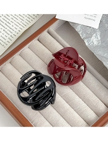 Macro shot of minimalist black and dark red hair claw clips with glossy striped texture