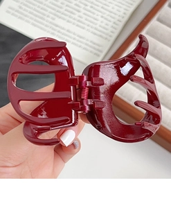 Detailed view of deep red glossy pumpkin hair claw clip showing polished texture and metal spring