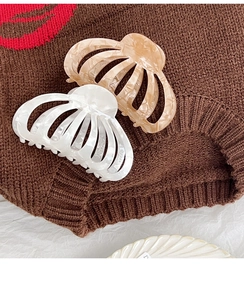 Détail de grandes pinces à cheveux texture marbre en acétate couleur crème et ambre