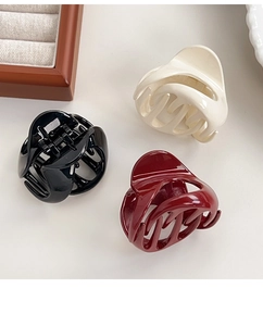 Detail of medium-sized pumpkin hair claws in black, cream, and wine red with glossy finish