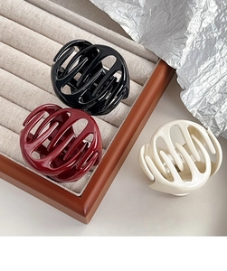 Close-up of three glossy hollow pumpkin-shaped hair claws in black, burgundy, and cream