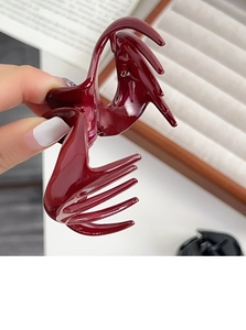 Close-up of a glossy wine red hair claw clip with metal spring mechanism for long hair