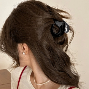 Elegant glossy black claw clip for women holding hair in a stylish half-up ponytail