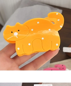 Détail de la pince à cheveux chat en acétate orange avec des pois blancs mignons