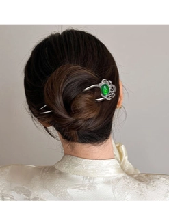 U-shaped hair pin detail with hollow flower pattern and green gemstone on white attire