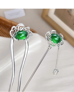 Detail of silver U-shaped hair pin and straight stick with green gemstone and tassels