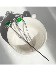 Close-up of U-shaped hair pin with silver hollow flower pattern and green stone inlay