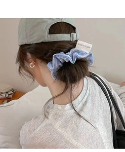 Close-up of blue and white striped fabric scrunchie with Made in Korea tag on hair