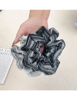 Detail of a ruffled scrunchie with classic black and white stripes and wavy texture