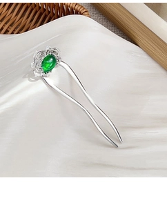 Detail of vintage silver U-shaped hair pin with green gemstone and floral carving