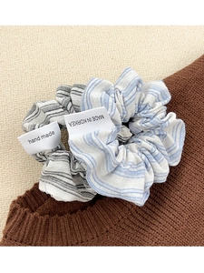 Detailed view of handmade blue and black striped scrunchies with textile labels