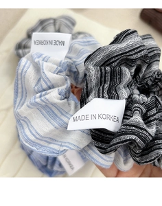 Macro detail of striped scrunchies with white lace trim and Made in Korea labels