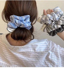 Close-up of a blue striped scrunchie with a handmade tag worn in a bun hairstyle