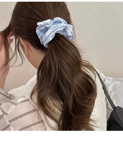 Close-up of blue and white striped fabric scrunchie worn on a ponytail hair style