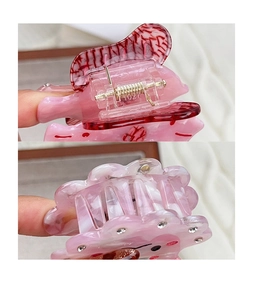 Vue détaillée des pinces à cheveux en acétate rose avec strass et ressort doré