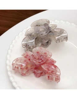 Details von Blumen-Haarklammern aus Acetat in Pfirsichrosa und Tintengrau auf Teller