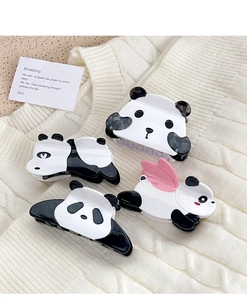 Dettaglio di quattro graziose mollette panda in acetato su un morbido tessuto a maglia