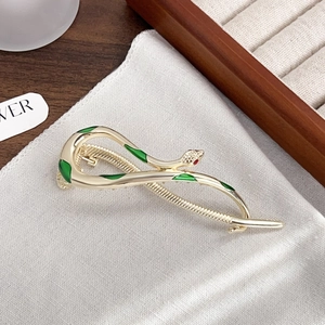 Gold snake hair claw clip with green enamel inlay and red rhinestone eyes detail
