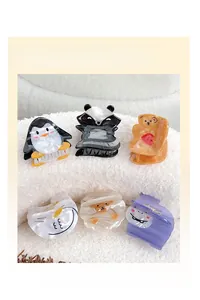 Detail showing six cartoon animal hair claw clips with marble texture on plush surface