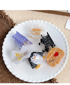 Detailed view of six cute acetate cartoon hair claws including penguin and toast designs