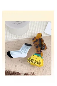 Detail view of acetate hair claw clips in creative sock and wavy cartoon shapes