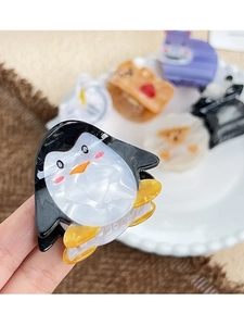 Macro detail of a cute penguin acetate hair claw clip with smooth marbled texture