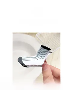 Detailed close-up of a white sock-shaped hair claw with green stripes on a ceramic bowl
