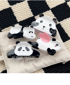Dettaglio di quattro graziose mollette per capelli a forma di panda in acetato lucido bianco e nero