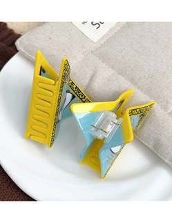 Détail de pinces à cheveux en acétate jaune et bleu avec motifs d'yeux de démon