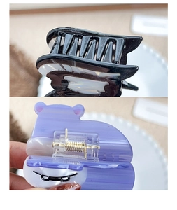 Detail of cute acetate hair claws with a black wavy design and purple cartoon bear style