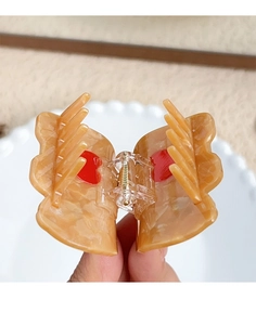 Close-up of amber acetate hair claw clip with red heart detail and gold metal spring