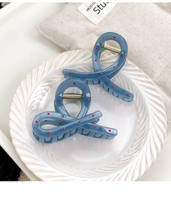 Detail of blue polka dot hair claws with metal springs in a white decorative bowl