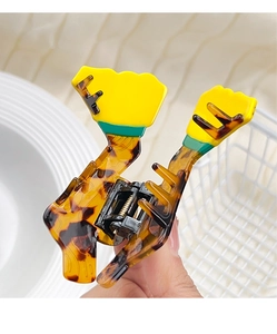 Macro detail of tortoiseshell acetate claw clip with yellow and green trash can accents