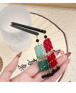 Détail d'épingles à cheveux chinoises Xi rouges et vertes avec pompons en main
