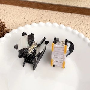Cute acetate panda and penguin hair claws displayed on a decorative ceramic tray