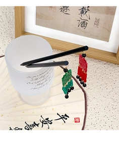 Détail des pompons de caractères Xi rouges et verts sur des épingles à cheveux chinoises