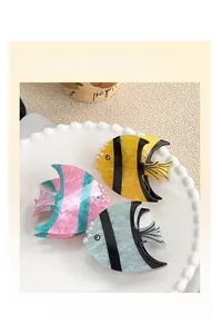 Détail de pinces à cheveux en forme de poisson coloré avec perles sur une assiette